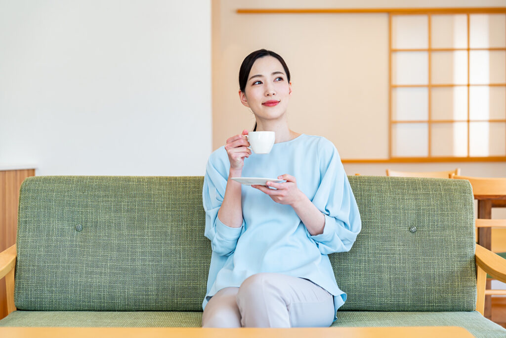 ソファーに座ってドリンクを飲む女性